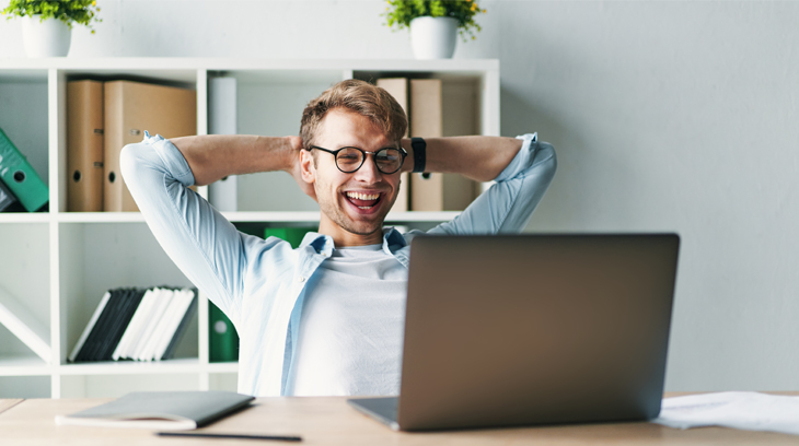 Een man met een bril zit blij achter zijn laptop